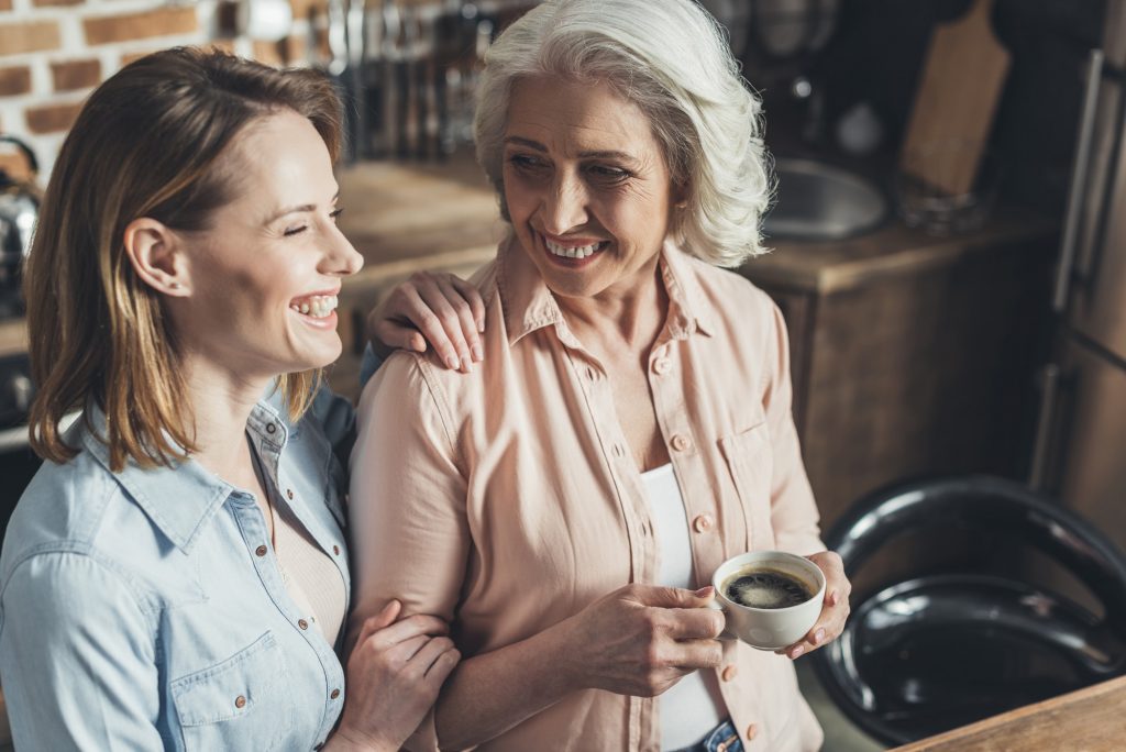 adult daughter talking with senior mother in kitchen
