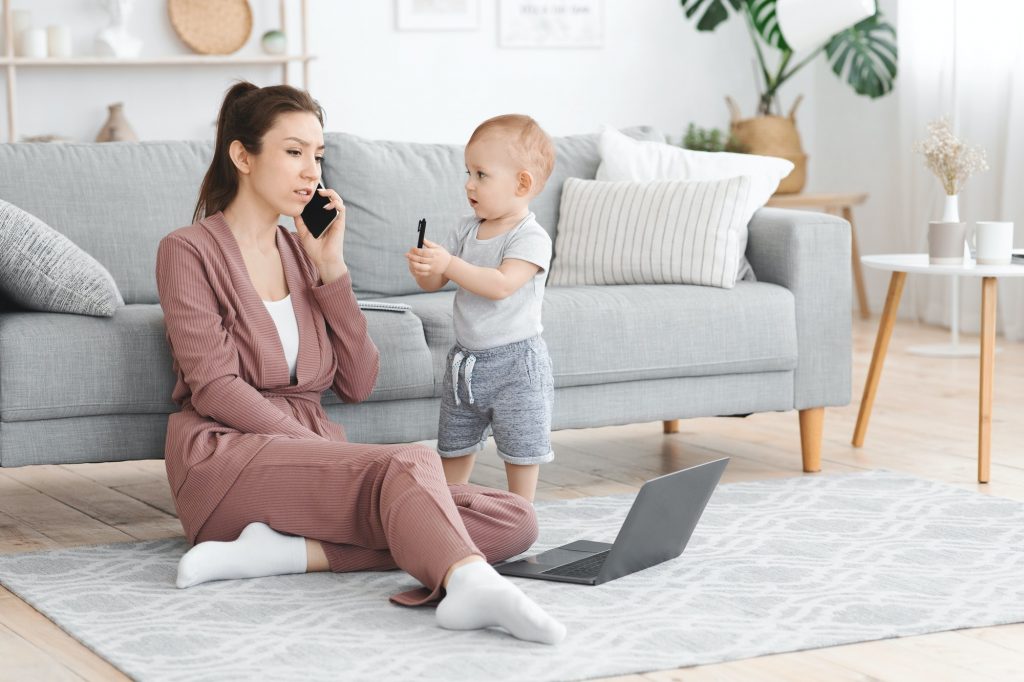 Busy Mom Answering Phone While Taking Care About Baby At Home