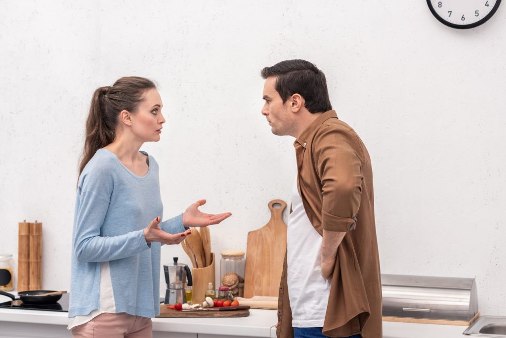 side view of adult couple having quarrel at kitchen